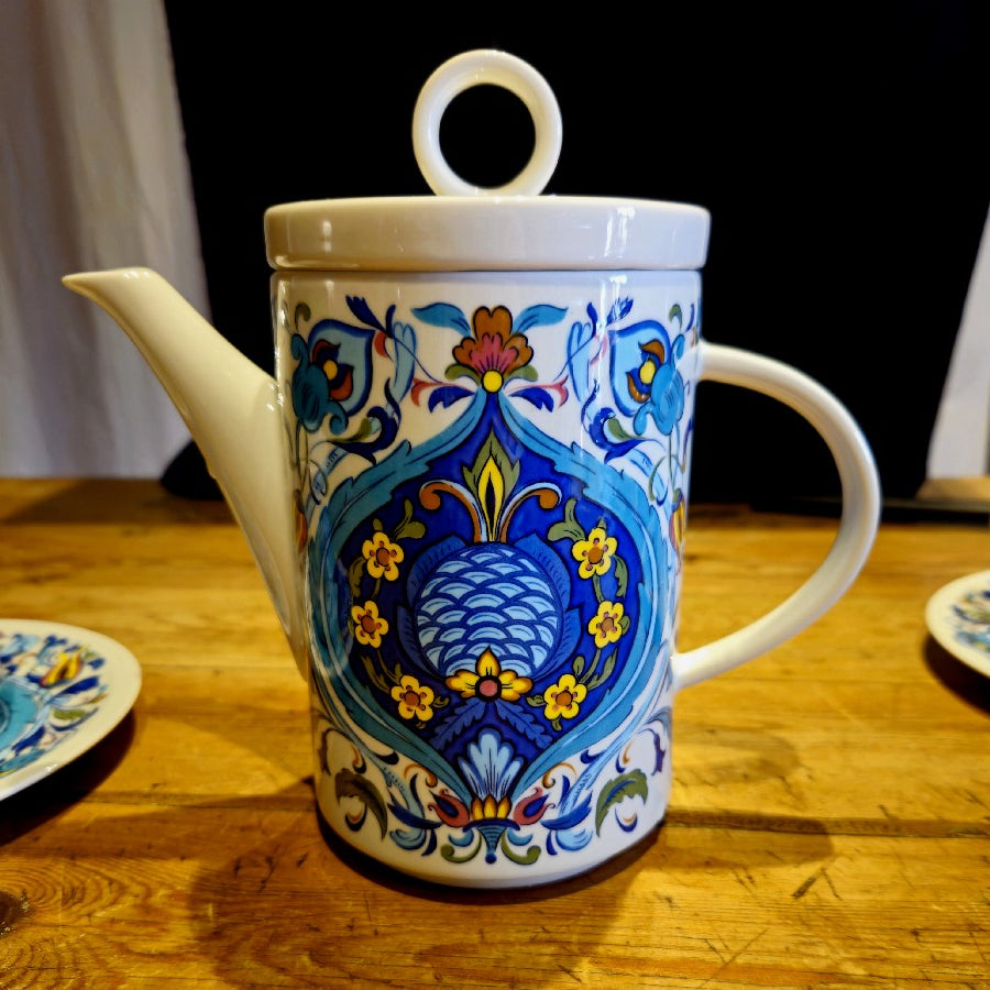 Cafetière (ou théière) colorées bleue jaune et brique. les différents tons de bleus et la symétrie des motifs donnent un coté oriental au décor.
le décor est identique des 2 cotés !
un couvercle dont l'anse est en forme d'anneau est présent sur la cafetière.