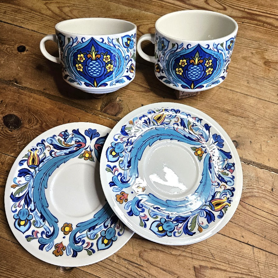 2 tasses et leurs sous tasses colorées bleue jaune et brique. les différents tons de bleus et la symétrie des motifs donnent un coté oriental au décor.
