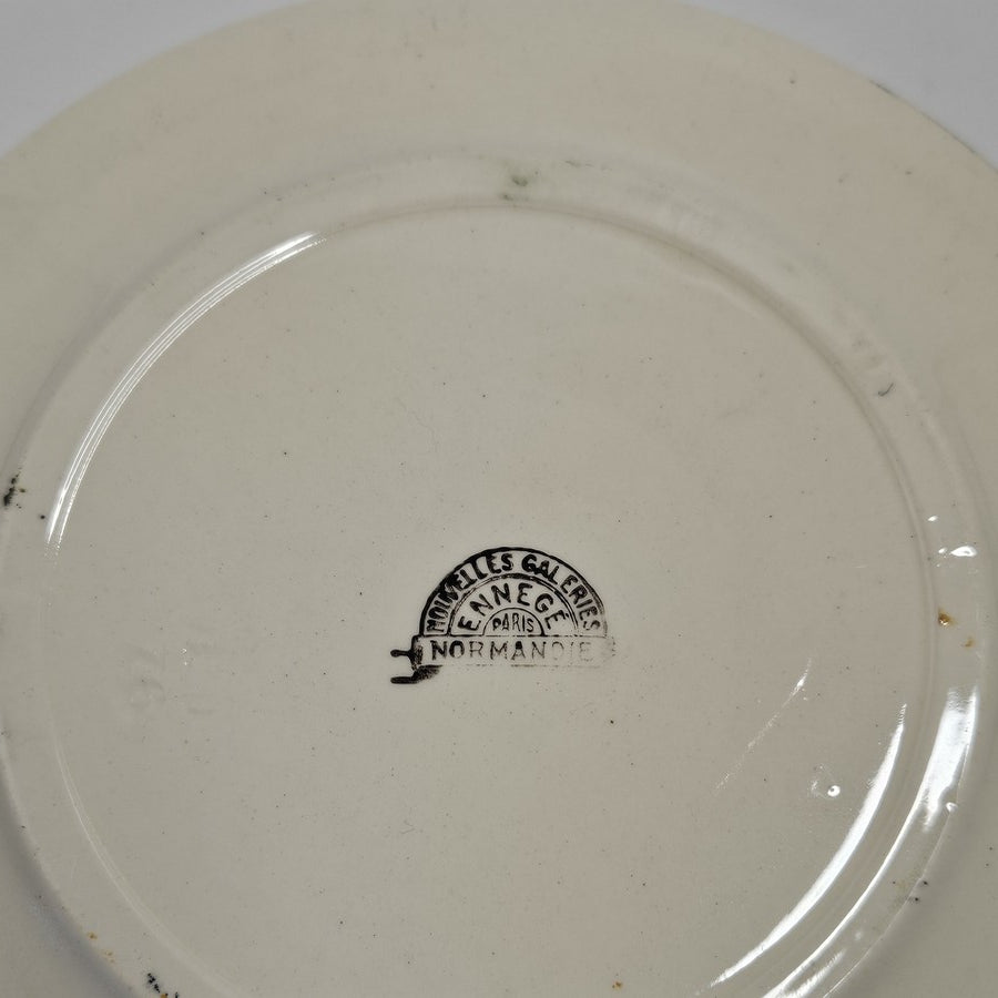 Marques minimes du temps (comme tout le monde !)
Sous l'assiette se trouve un tampon  :
en arc de cercle sur le haut : NOUVELLES GALERIES
Dessous : ENNEGÉ
et droit pour la base : NORMANDIE