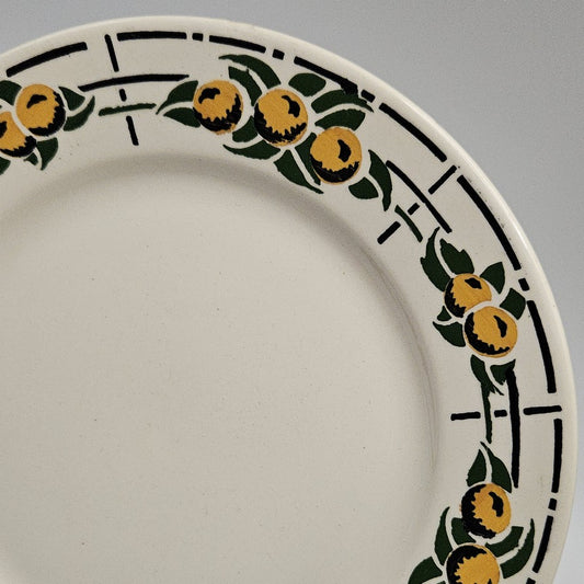 De couleur beige très pâle, comme beaucoup de faïences, cette assiette est entourée de fruits ronds jaunes avec des ombres noires prononcées sur le bas de chaque fruit en séquence de 3 - 2 - 3 - 2 . Chaque séquence est entourée de feuilles vertes et le tout est posé sur un fin quadrillé noir. Les couleurs sont chatoyantes.
23.5cm de diamètre
Aucune restauration
