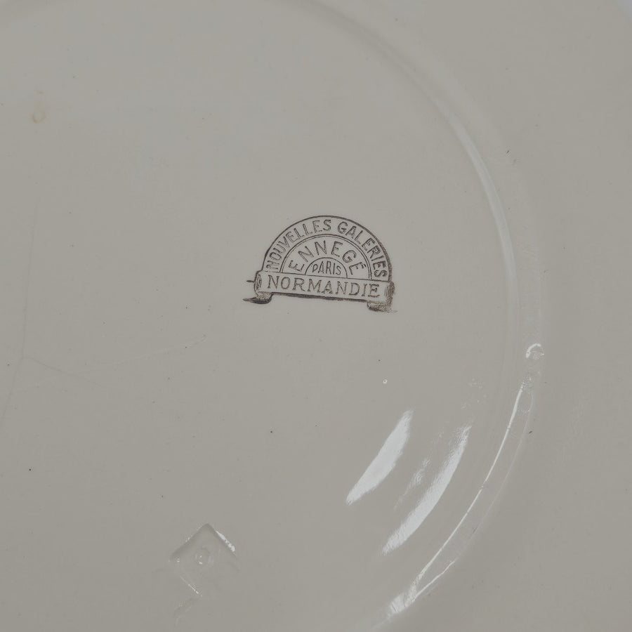 Marques minimes du temps (comme tout le monde !)
Sous l'assiette se trouve un tampon  :
en arc de cercle sur le haut : NOUVELLES GALERIES
Dessous : ENNEGÉ
et droit pour la base : NORMANDIE