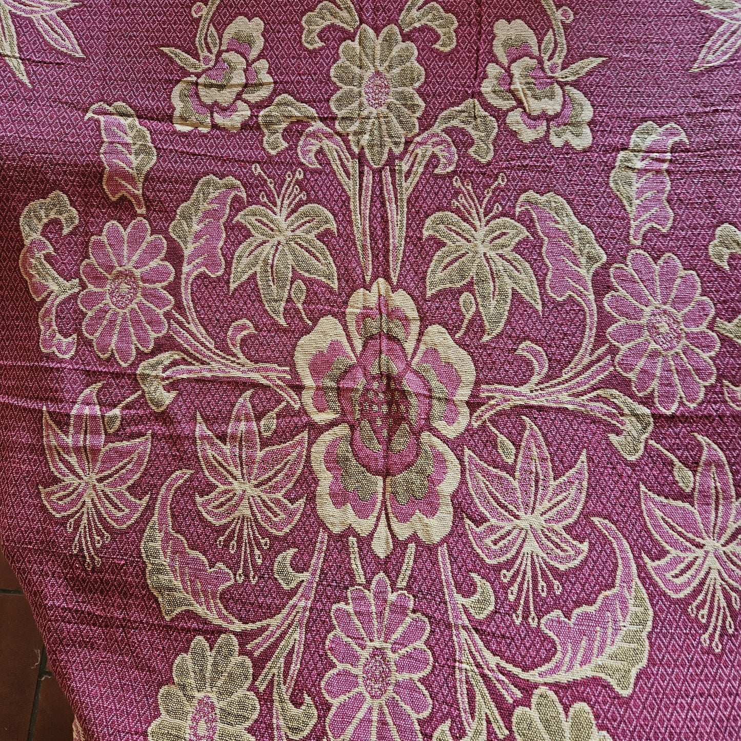 Détail du médaillon central du jeté de lit en jacquard double face années 1950-1960, face endroit fond framboise/bordeaux, montrant la composition florale symétrique de fuchsias, anémones et dahlias en camaïeu rose/crème/vert olive.