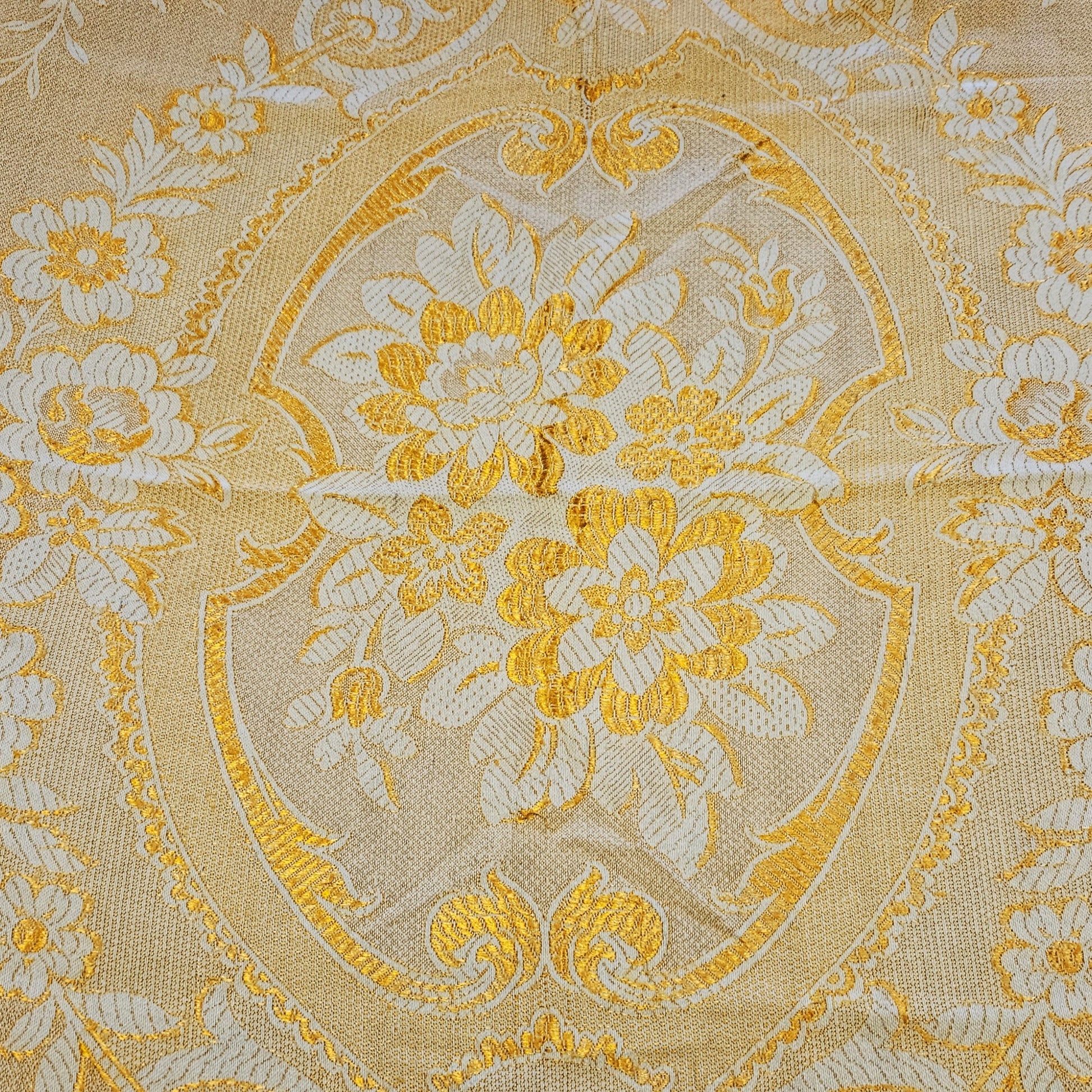 Détail du médaillon central en cartouche à écusson du jeté de canapé en jacquard double face années 1950-1960, face envers fond or/jaune intense, montrant le bouquet de pivoines et anémones en crème entouré de rinceaux et volutes Baroque, avec frise florale à roses en bordure.