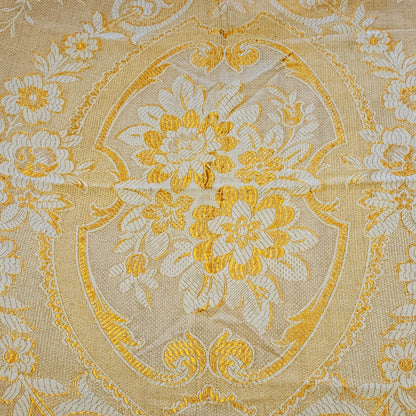 Détail du médaillon central en cartouche à écusson du jeté de canapé en jacquard double face années 1950-1960, face envers fond or/jaune intense, montrant le bouquet de pivoines et anémones en crème entouré de rinceaux et volutes Baroque, avec frise florale à roses en bordure.