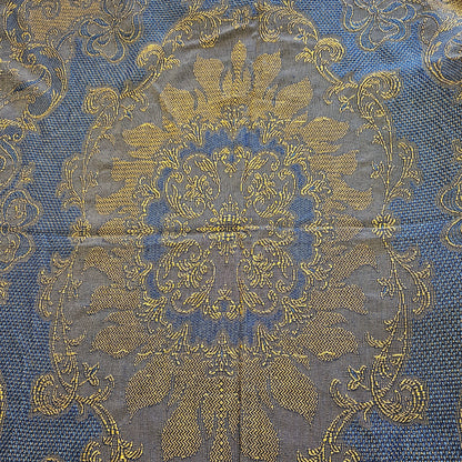 Détail du médaillon central du jeté de canapé en jacquard double face années 1950-1960, face endroit bleu roi, montrant le vase fleuri symétrique avec bouquet de fleurs et feuillages en jaune doré, encadré de bandes à chevrons et rinceaux latéraux en volutes, sur fond bleu roi intense.