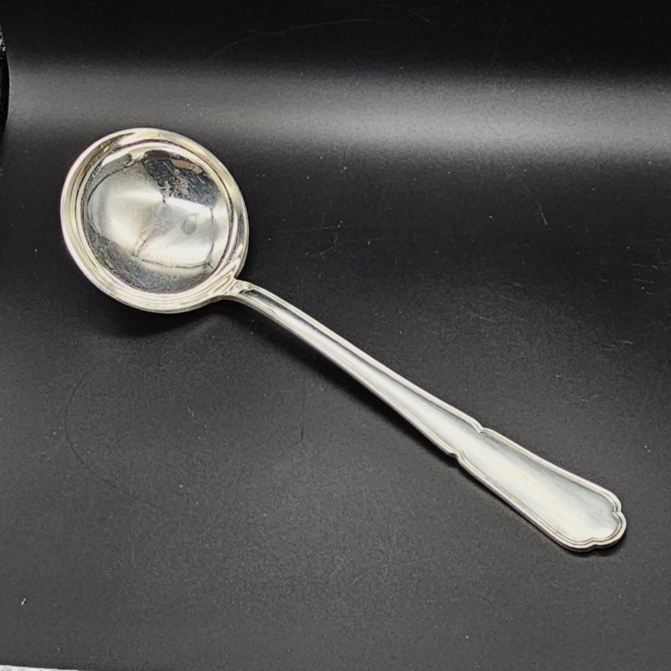 Louche à potage en métal argenté modèle Filet contour, 30,5 cm, vue de face sur fond noir, montrant la cuillère ronde et profonde et le long manche à double filet avec extrémité en trèfle.