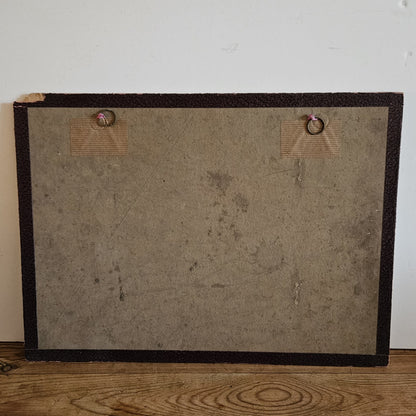 Vue du dos du cadre de l'aquarelle de Paul Friesé, montrant un fond en carton brun avec deux anneaux de suspension fixés par des étiquettes en carton, posé sur un parquet en bois brut.