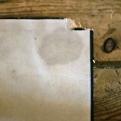 Gros plan sur le coin supérieur droit du cadre de l'aquarelle, montrant une légère déchirure du carton de fond, ainsi que la tache d'humidité due au collage de l'aquarelle sur le carton de fond, le tout est le témoignage de l'ancienneté de la pièce. 