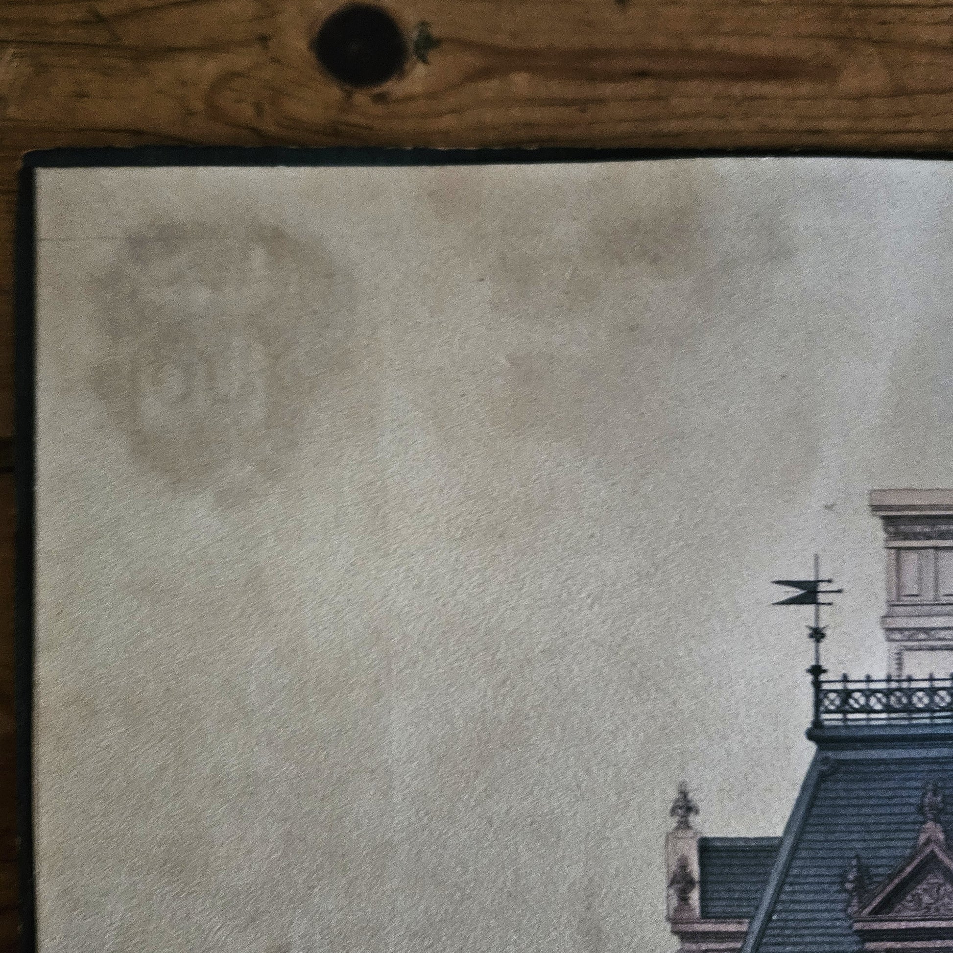 Gros plan sur le coin supérieur gauche de l'aquarelle de Paul Friesé, montrant des rousseurs et légères taches d'humidité dues au collage du papier sur le carton, avec un fragment de toiture Second Empire visible en bas à droite.