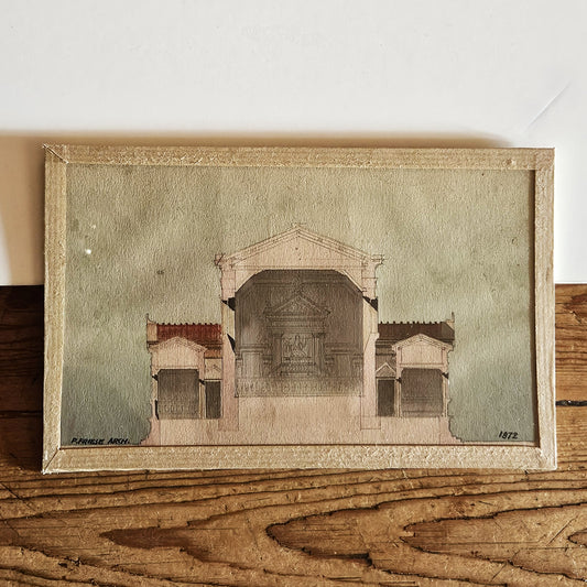 Aquarelle originale encadrée de Paul Friesé, représentant la coupe longitudinale d'un édifice religieux néo-classique avec portique à fronton, colonnes corinthiennes et autel monumental, signée P. Friese Arch. et datée 1872, dans un cadre en papier texturé beige, posée sur une table en bois brut.