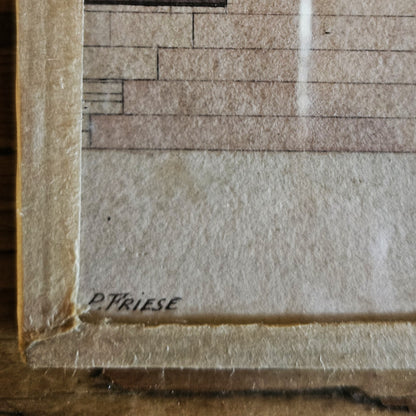Gros plan sur le coin inférieur gauche de l'aquarelle de Paul Friesé, montrant la signature manuscrite « P. FRIESE » à l'encre noire sur le papier vergé beige, avec le bord du cadre en papier texturé beige visible, posé sur une table en bois brut.