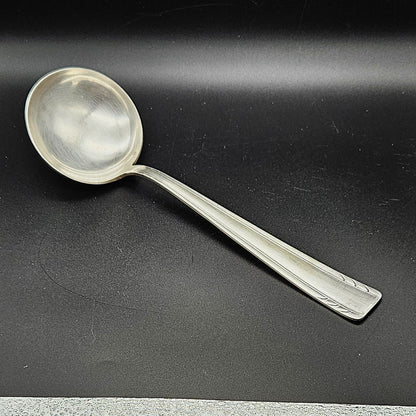 Louche à potage en métal argenté Art Déco, 30 cm, vue de face sur fond noir, montrant la cuillère ronde et profonde avec bourrelet de jonction et le manche rectangulaire effilé à double filet latéral.