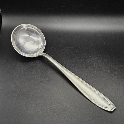 Louche à potage en métal argenté orfèvre Apollo, 32,2 cm, vue de face sur fond noir, montrant la cuillère ronde et profonde avec bourrelet périphérique et le manche fusiforme effilé à double filet latéral convergent.